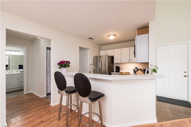 5088 Heathglen Cir, Virginia Beach, VA 23456 - kitchen with freestanding refrigerator, light countertops, a kitchen bar, white cabinets, and a textured ceiling