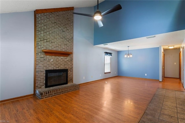 1121 Millay Ct, Virginia Beach, VA 23454 - unfurnished living room with a chandelier, wood finished floors, high vaulted ceiling, a brick fireplace, and a ceiling fan