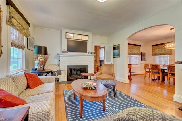 1357 Buckingham Ave, Norfolk, VA 23508 - living room with arched walkways, wood finished floors, a brick fireplace, crown molding, and a baseboard radiator