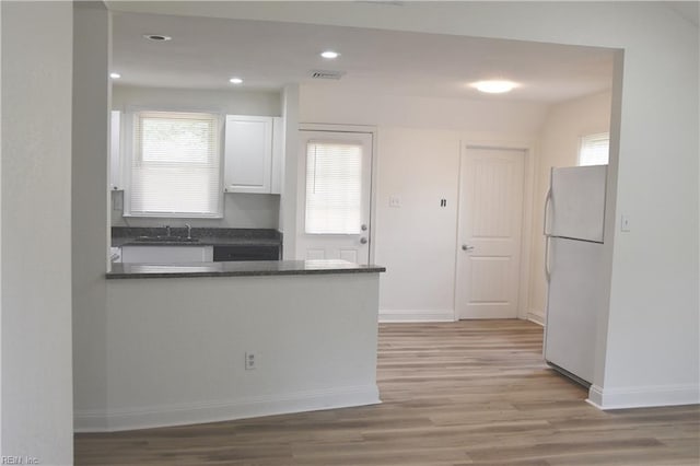 1910 N Lakeland Dr, Norfolk, VA 23518 - kitchen featuring freestanding refrigerator, dark countertops, white cabinets, light wood-type flooring, and a peninsula