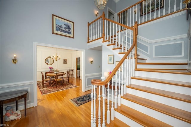 1040 Sanderson Rd, Chesapeake, VA 23322 - stairs featuring a chandelier, a high ceiling, a decorative wall, wood finished floors, and a wainscoted wall