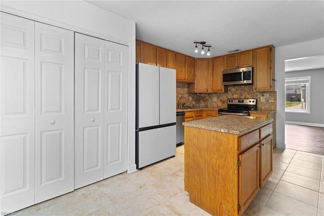 114 Lancelot Dr, Suffolk, VA 23434 - kitchen with appliances with stainless steel finishes, decorative backsplash, a center island, brown cabinetry, and light tile patterned flooring