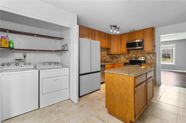 114 Lancelot Dr, Suffolk, VA 23434 - kitchen featuring stainless steel appliances, independent washer and dryer, decorative backsplash, a center island, and light tile patterned flooring