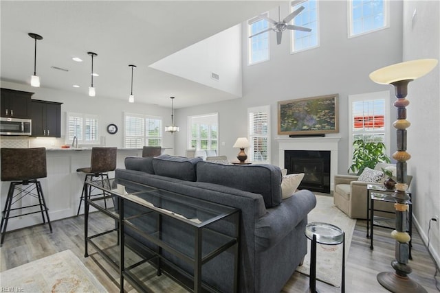 1041 Whitburn Ter, Chesapeake, VA 23322 - living room featuring a ceiling fan, light wood-style flooring, a fireplace with flush hearth, recessed lighting, and a towering ceiling