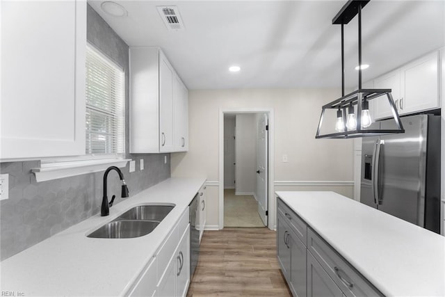 2001 Blackwell Ct, Virginia Beach, VA 23464 - kitchen with appliances with stainless steel finishes, light countertops, light wood-type flooring, white cabinetry, and backsplash