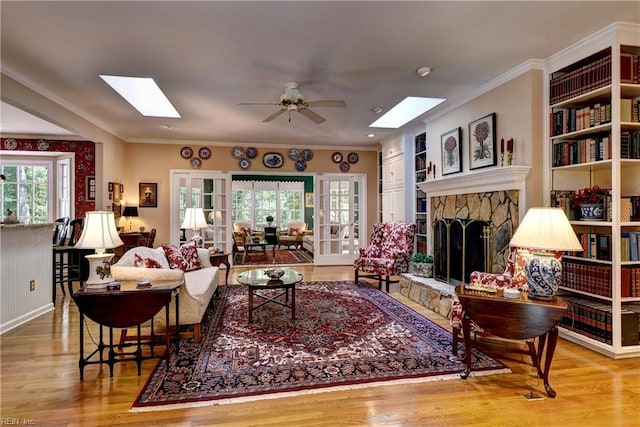 8265 Wrenfield Dr, Williamsburg, VA 23188 - living area with a skylight, wood finished floors, a ceiling fan, a stone fireplace, and crown molding