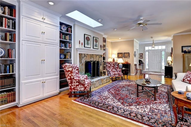 8265 Wrenfield Dr, Williamsburg, VA 23188 - living area with crown molding, light wood-style floors, a fireplace, ceiling fan, and a skylight