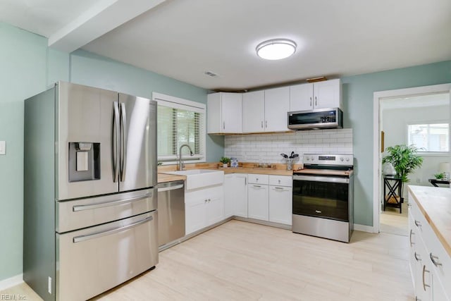 331 Silina Ct, Virginia Beach, VA 23452 - kitchen with stainless steel appliances, decorative backsplash, white cabinetry, light wood-type flooring, and butcher block counters