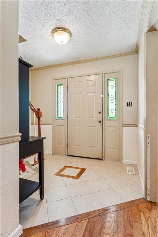 102 Canvasback Trl, Newport News, VA 23602 - entryway with crown molding, a textured ceiling, stairs, and light tile patterned flooring
