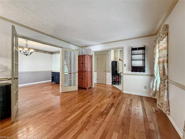 102 Canvasback Trl, Newport News, VA 23602 - unfurnished living room featuring light wood-style flooring, ornamental molding, a chandelier, a textured ceiling, and french doors