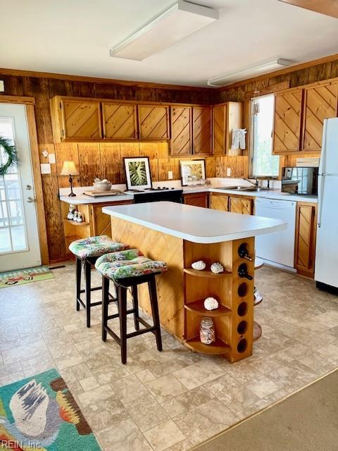 3225 Sandfiddler Rd, Virginia Beach, VA 23456 - kitchen featuring white appliances, wood walls, brown cabinetry, light countertops, and a center island
