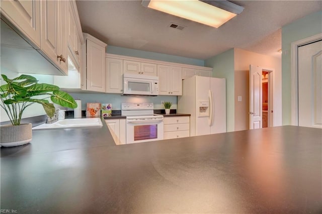 307 Melrose Ct, Suffolk, VA 23434 - kitchen featuring white appliances, dark countertops, a peninsula, and white cabinets