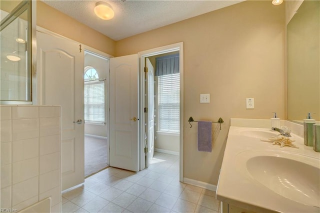 307 Melrose Ct, Suffolk, VA 23434 - bathroom featuring plenty of natural light, double vanity, tile patterned flooring, a shower with shower door, and a textured ceiling