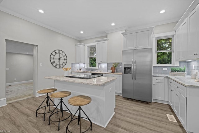 2233 Keller Ave, Norfolk, VA 23509 - kitchen with stainless steel refrigerator with ice dispenser, a center island, ornamental molding, backsplash, and a kitchen bar