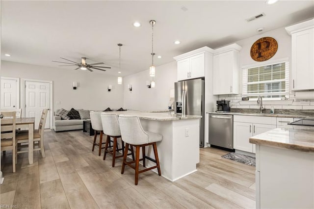 401 W 30th St, Norfolk, VA 23508 - kitchen with appliances with stainless steel finishes, a kitchen island, a breakfast bar area, light wood-type flooring, and white cabinets