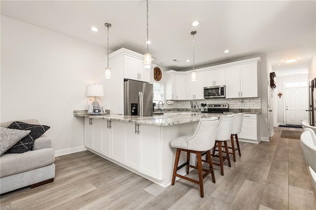 401 W 30th St, Norfolk, VA 23508 - kitchen with stainless steel appliances, a peninsula, light stone counters, white cabinetry, and recessed lighting