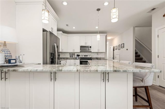 401 W 30th St, Norfolk, VA 23508 - kitchen with appliances with stainless steel finishes, white cabinets, a kitchen breakfast bar, a peninsula, and light wood-type flooring