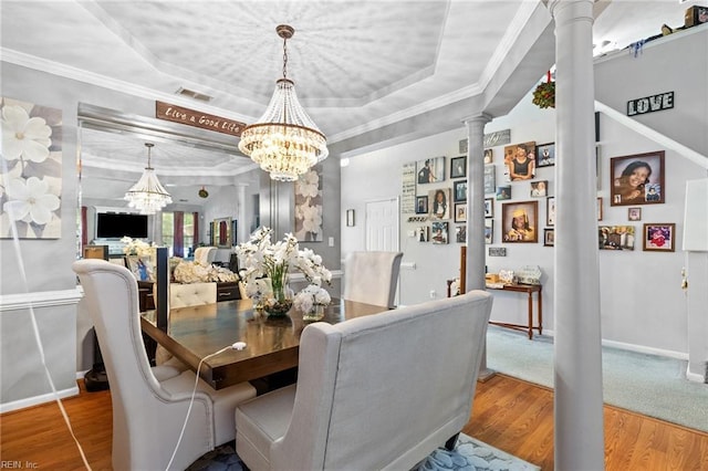 1058 Hillpoint Rd, Suffolk, VA 23434 - dining space featuring decorative columns, a raised ceiling, wood finished floors, a chandelier, and ornamental molding