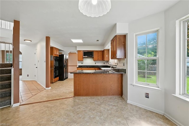 700 Hilltop Ct, Chesapeake, VA 23322 - kitchen featuring a peninsula, brown cabinets, dark countertops, and healthy amount of natural light