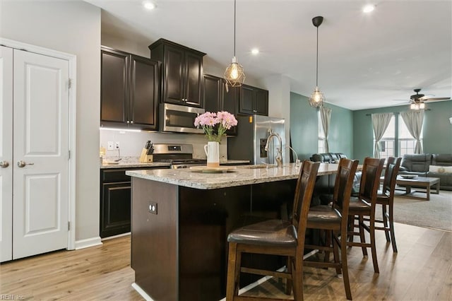 112 Mccormick Pl, Williamsburg, VA 23185 - kitchen with stainless steel appliances, a kitchen island with sink, open floor plan, a kitchen bar, and light wood-style floors