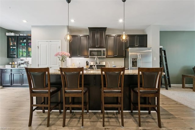 112 Mccormick Pl, Williamsburg, VA 23185 - kitchen with stainless steel appliances, pendant lighting, glass insert cabinets, a center island with sink, and a kitchen bar