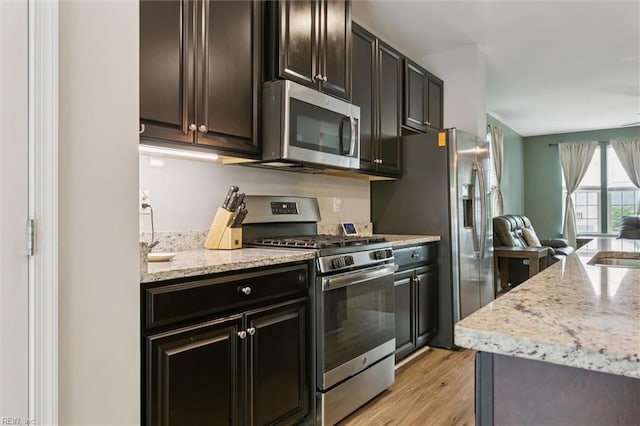 112 Mccormick Pl, Williamsburg, VA 23185 - kitchen featuring appliances with stainless steel finishes, open floor plan, light stone counters, light wood-style flooring, and dark brown cabinetry