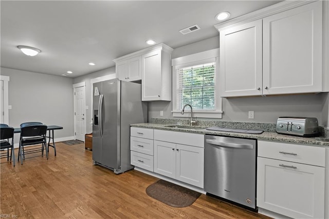 2309 Drum Creek Rd, Chesapeake, VA 23321 - kitchen with stainless steel appliances, white cabinets, recessed lighting, light stone counters, and wood finished floors