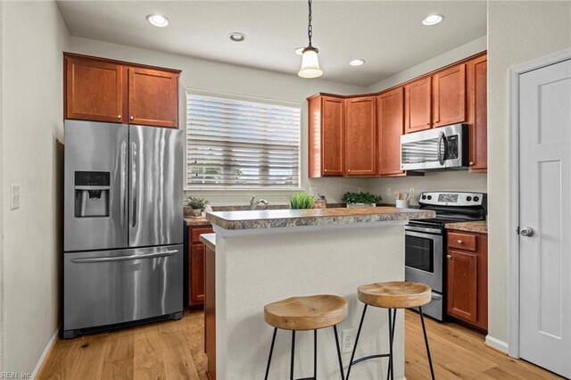 616 Foster Ln, Virginia Beach, VA 23451 - kitchen featuring stainless steel appliances, a center island, light wood finished floors, hanging light fixtures, and a kitchen breakfast bar