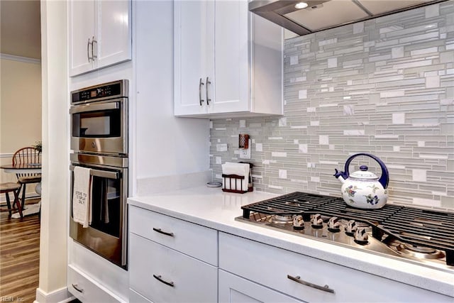 3998 Isaac Cir, Williamsburg, VA 23188 - kitchen with appliances with stainless steel finishes, ventilation hood, white cabinetry, tasteful backsplash, and light countertops