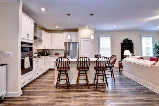 3998 Isaac Cir, Williamsburg, VA 23188 - kitchen featuring appliances with stainless steel finishes, open floor plan, wall chimney exhaust hood, a kitchen bar, and white cabinets