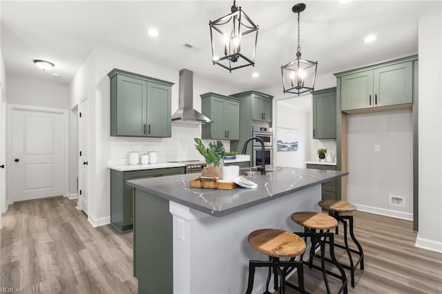 140 Benefit Rd, Chesapeake, VA 23322 - kitchen with wall chimney exhaust hood, green cabinetry, light wood-type flooring, a chandelier, and backsplash