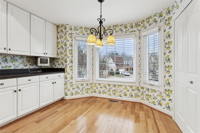 367 Mainsail Dr Unit 23, Hampton, VA 23664 - kitchen featuring wallpapered walls, a chandelier, light wood-style flooring, white cabinets, and dark countertops