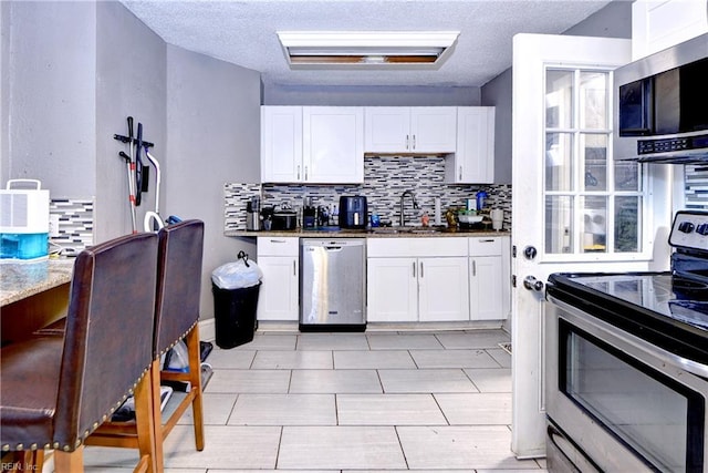 387 Sampson Ave, Hampton, VA 23661 - kitchen featuring appliances with stainless steel finishes, decorative backsplash, white cabinetry, a textured ceiling, and dark stone counters