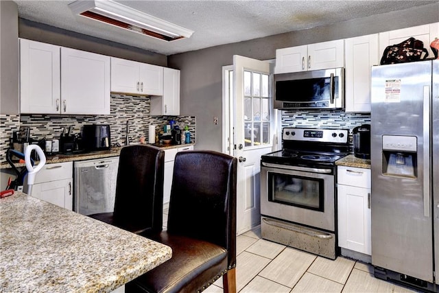 387 Sampson Ave, Hampton, VA 23661 - kitchen featuring stainless steel appliances, decorative backsplash, white cabinetry, and a textured ceiling
