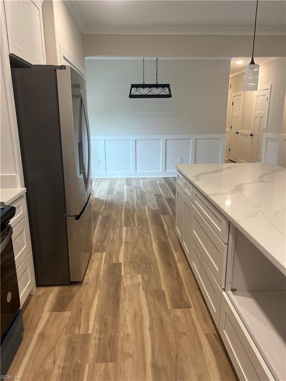 1635 E Bayview Blvd, Norfolk, VA 23503 - kitchen with freestanding refrigerator, a decorative wall, wood finished floors, crown molding, and white cabinets