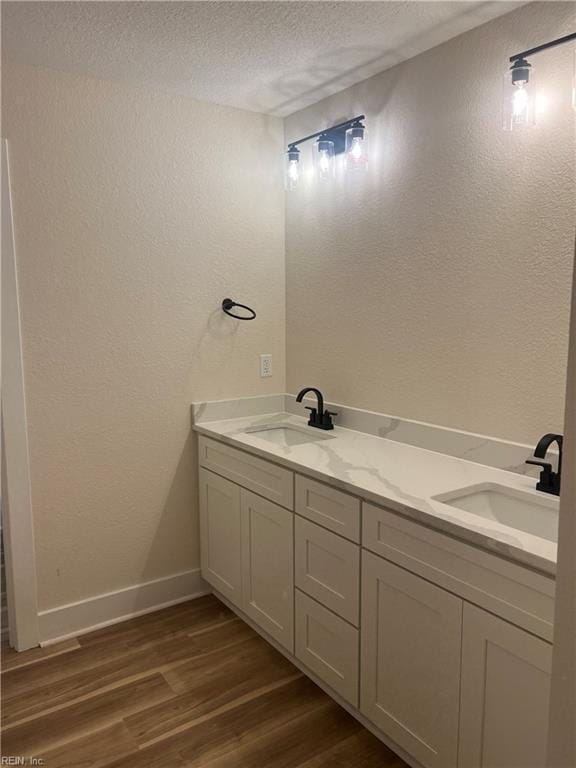 1635 E Bayview Blvd, Norfolk, VA 23503 - bathroom featuring wood finished floors, a textured wall, a textured ceiling, and double vanity