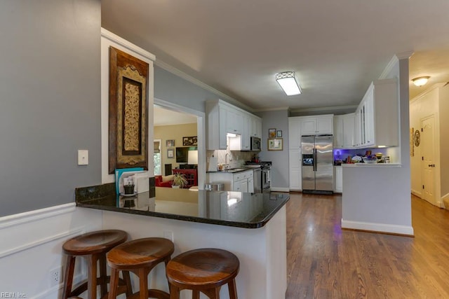 1208 Smith Cove Cir, Virginia Beach, VA 23455 - kitchen with appliances with stainless steel finishes, a peninsula, white cabinets, crown molding, and dark wood-style floors