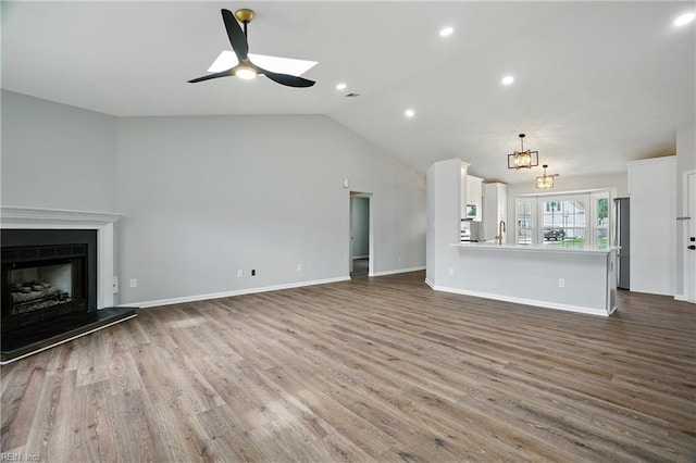 2317 Esplanade Dr, Virginia Beach, VA 23456 - unfurnished living room featuring wood finished floors, a ceiling fan, vaulted ceiling, a fireplace with raised hearth, and recessed lighting