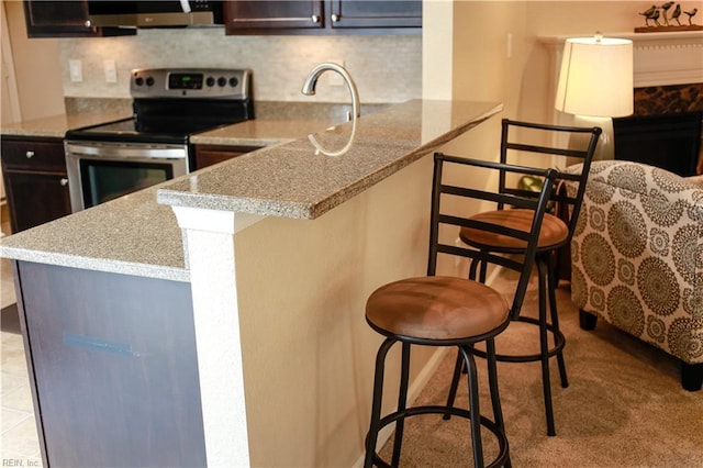911 Vineyard Pl Unit # C, Suffolk, VA 23435 - kitchen featuring electric range, a breakfast bar, backsplash, a peninsula, and light stone counters