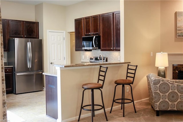 911 Vineyard Pl Unit # C, Suffolk, VA 23435 - kitchen featuring freestanding refrigerator, a kitchen bar, dark brown cabinets, backsplash, and a peninsula