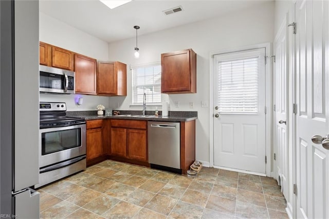 3116 Weathers Blvd, Toano, VA 23168 - kitchen featuring stainless steel appliances, dark countertops, brown cabinets, and light stone finish flooring