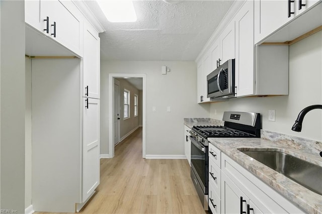 615 Hilton Blvd, Newport News, VA 23605 - kitchen with appliances with stainless steel finishes, light wood-type flooring, light stone counters, white cabinets, and a textured ceiling