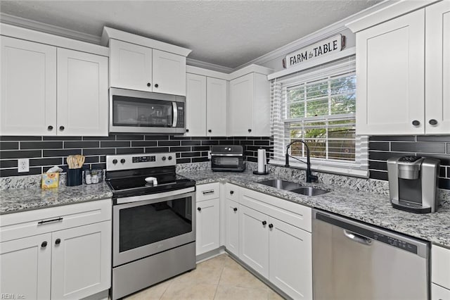 102 Dogwood Dr, Williamsburg, VA 23185 - kitchen with appliances with stainless steel finishes, ornamental molding, white cabinetry, light tile patterned flooring, and decorative backsplash