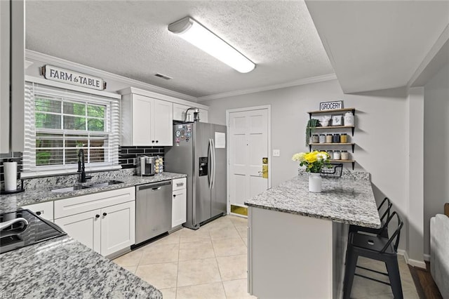 102 Dogwood Dr, Williamsburg, VA 23185 - kitchen featuring stainless steel appliances, a breakfast bar, white cabinetry, decorative backsplash, and crown molding