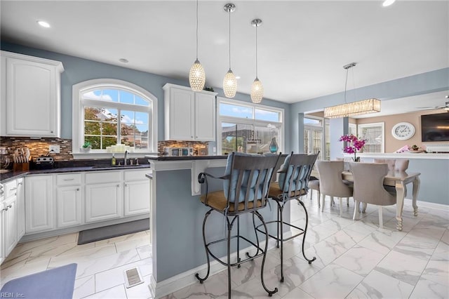 2224 Cabot Ct, Virginia Beach, VA 23456 - kitchen with light marble finish flooring, dark countertops, a breakfast bar, recessed lighting, and white cabinetry