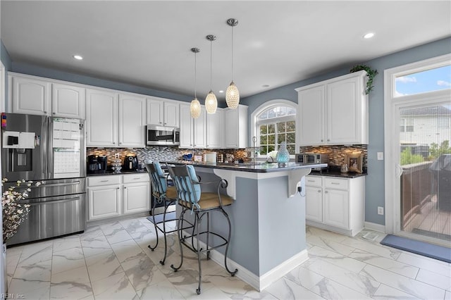 2224 Cabot Ct, Virginia Beach, VA 23456 - kitchen featuring appliances with stainless steel finishes, light marble finish flooring, dark countertops, a breakfast bar area, and white cabinetry