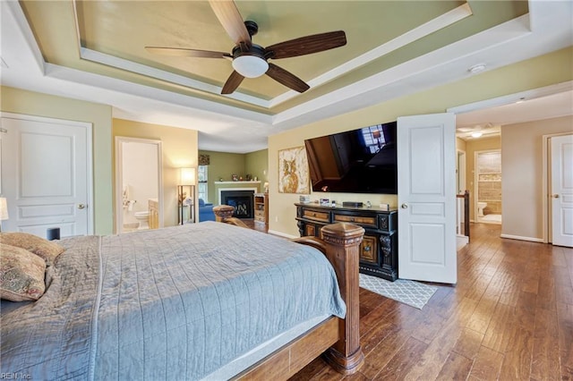 2060 Queens Point Dr, Suffolk, VA 23434 - bedroom with a raised ceiling, dark wood-style flooring, a fireplace, ensuite bath, and ceiling fan
