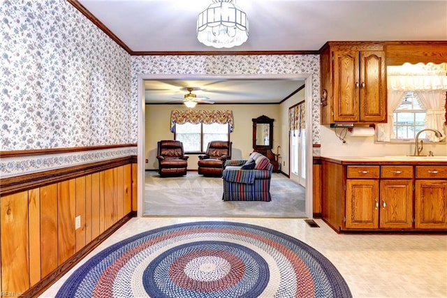 5 Yulee Ct, Hampton, VA 23669 - kitchen with ornamental molding, wallpapered walls, brown cabinetry, light countertops, and a wainscoted wall