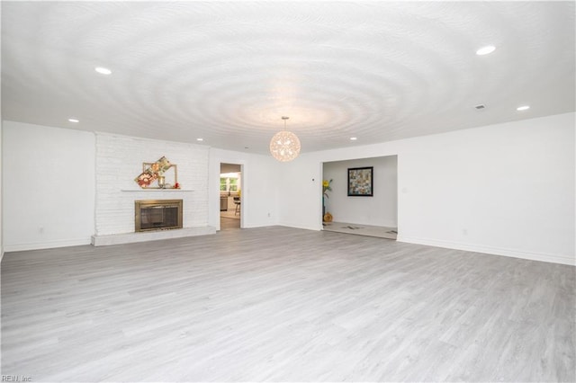 3760 Nansemond Pkwy, Suffolk, VA 23435 - unfurnished living room featuring light wood-style flooring, recessed lighting, a chandelier, and a brick fireplace