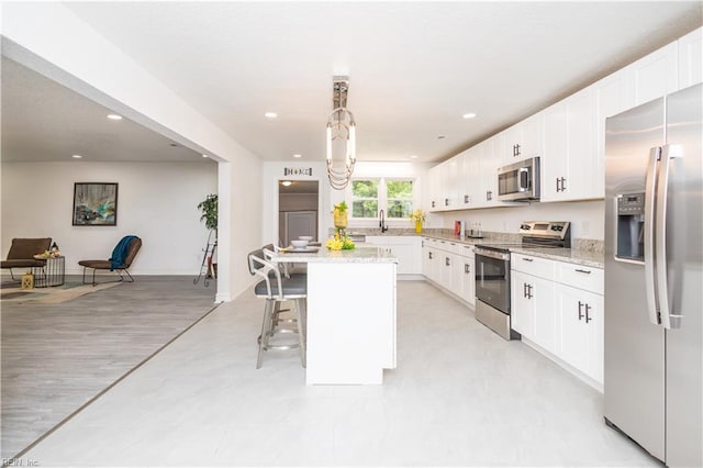 3760 Nansemond Pkwy, Suffolk, VA 23435 - kitchen with appliances with stainless steel finishes, a kitchen bar, a center island, white cabinetry, and recessed lighting